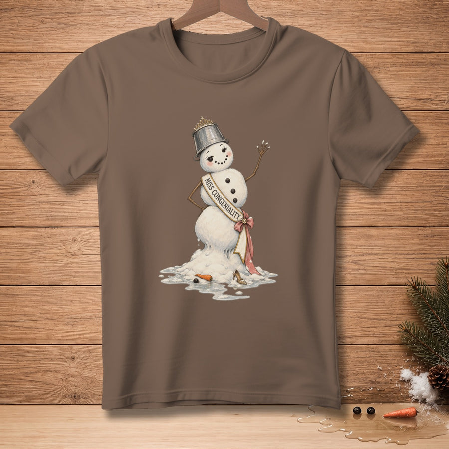 Melting snowman wearing a crown and "Miss Congeniality" sash, on a brown t-shirt.