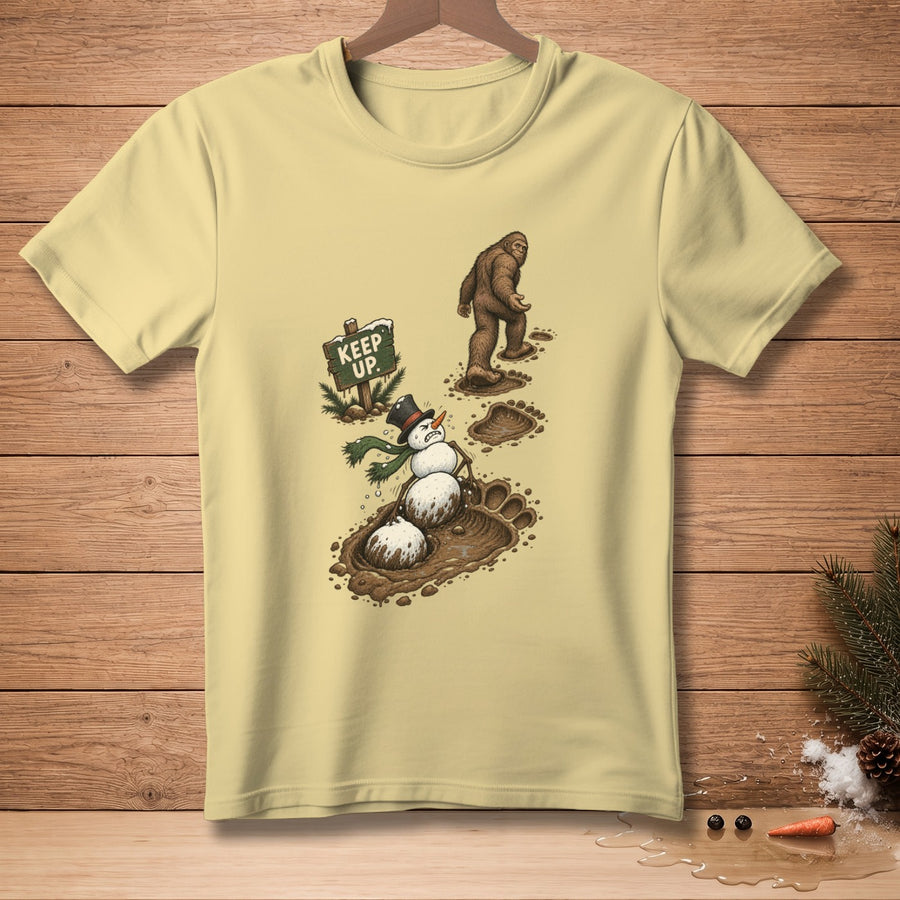 Bigfoot walks past a melting snowman with a sign saying "Keep Up."