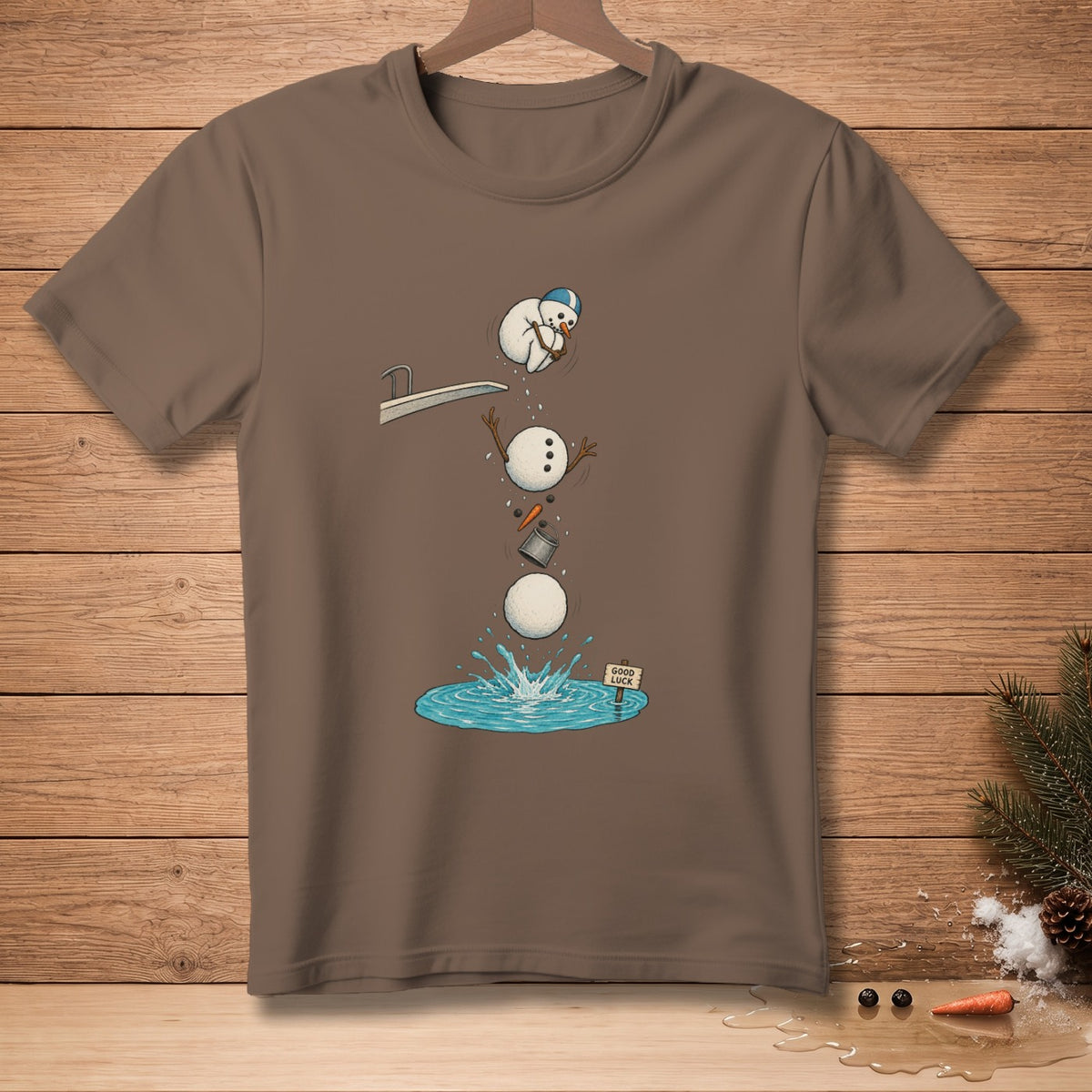 Brown t-shirt featuring a snowman falling apart into water with a "Good Luck" sign.