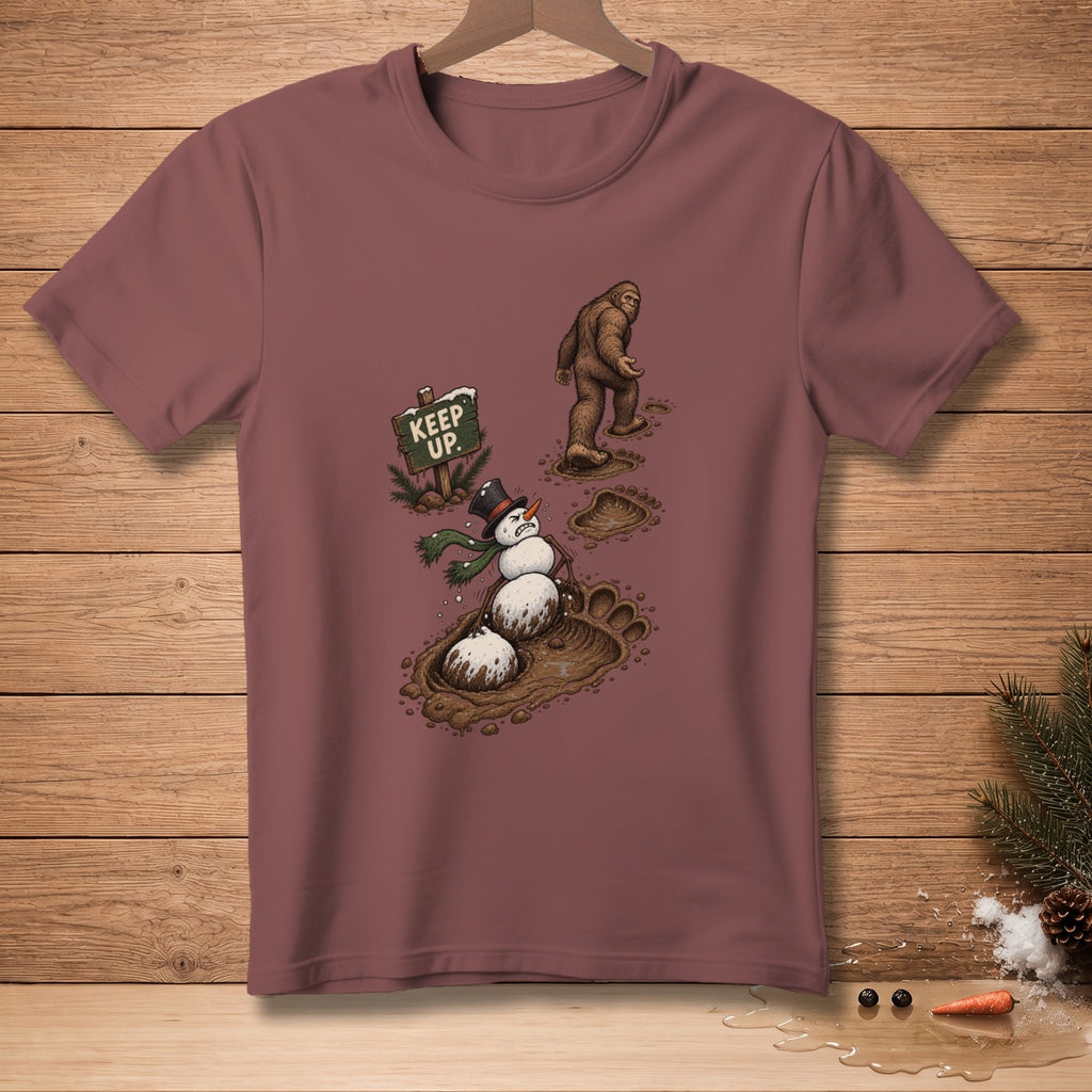Bigfoot walks past a snowman stuck in mud next to a "KEEP UP" sign.
