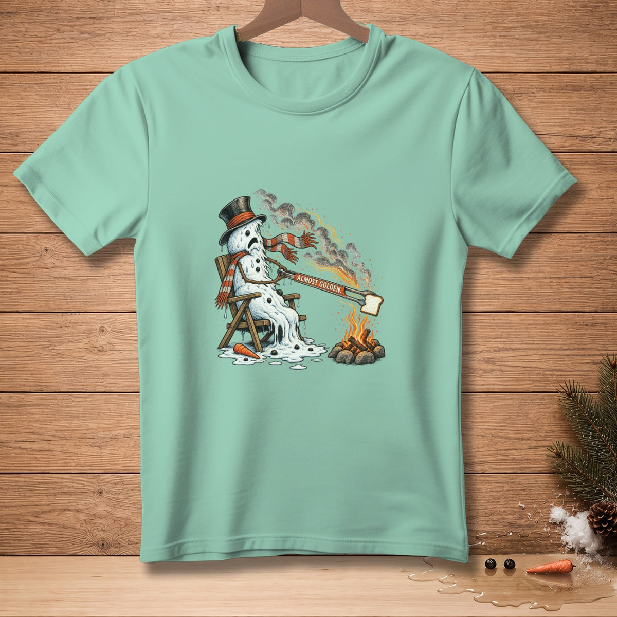 Melting snowman in a chair toasting bread by campfire, text "Almost Golden".