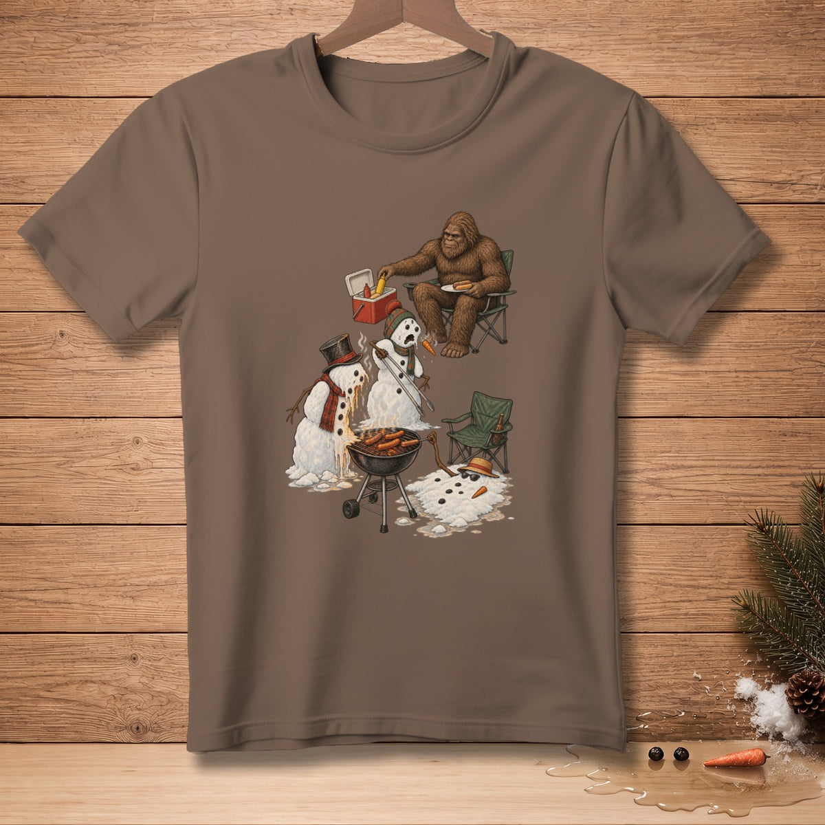 Bigfoot grilling hot dogs with melting snowmen on a brown t-shirt.