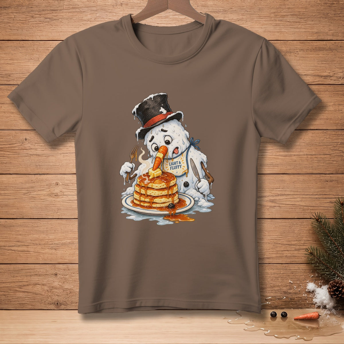 Melting snowman wearing a top hat eats pancakes with a carrot nose and "Light & Fluffy" bib.