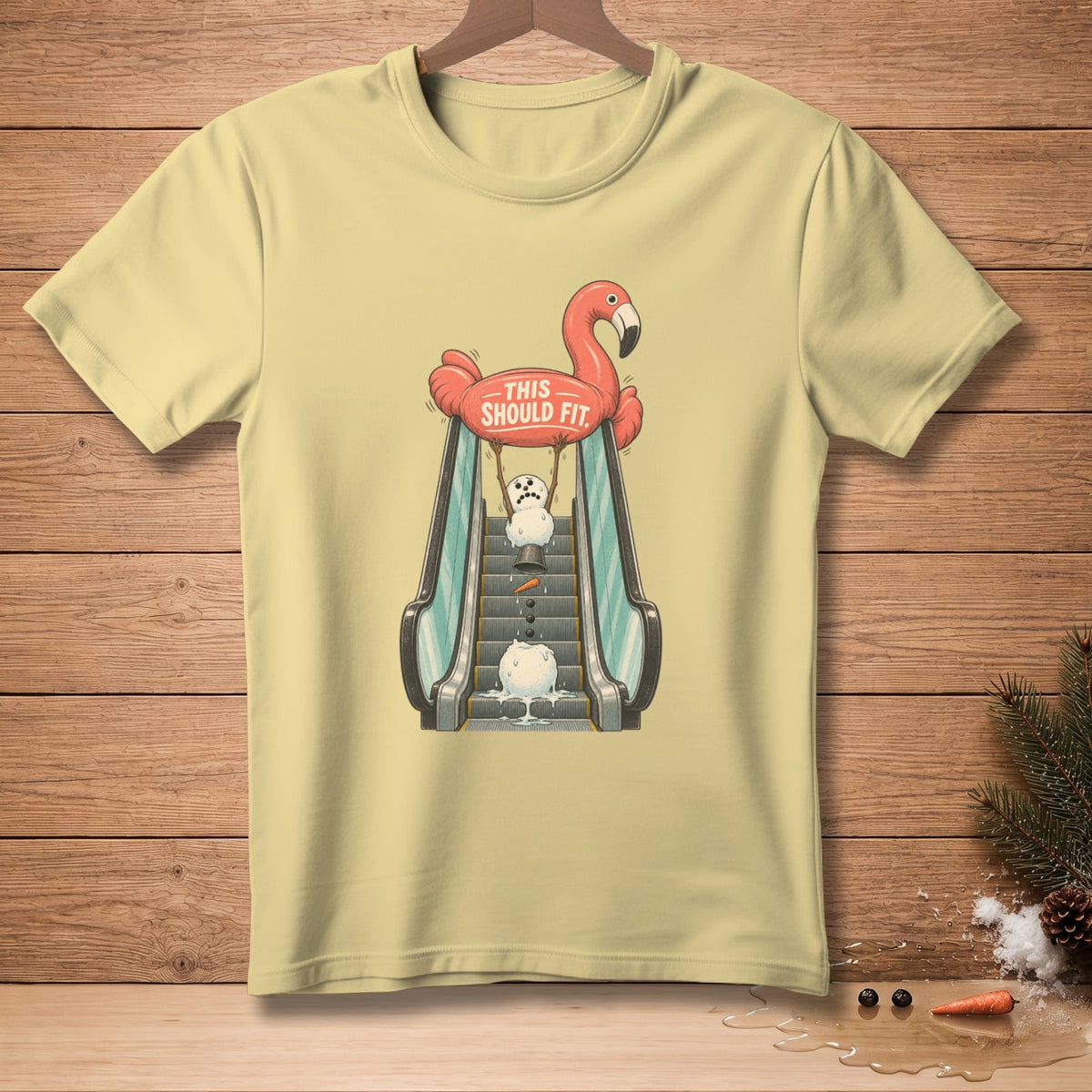 T-shirt with a flamingo holding a sign that says "This Should Fit" above a melting snowman on an escalator.