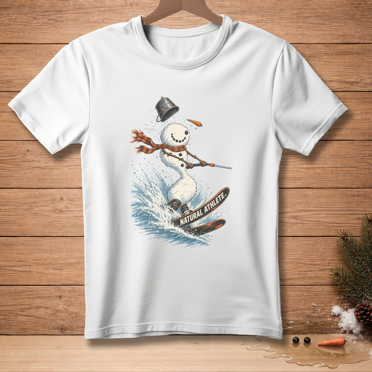 White t-shirt with snowman skiing through water, wearing a scarf and bucket hat.