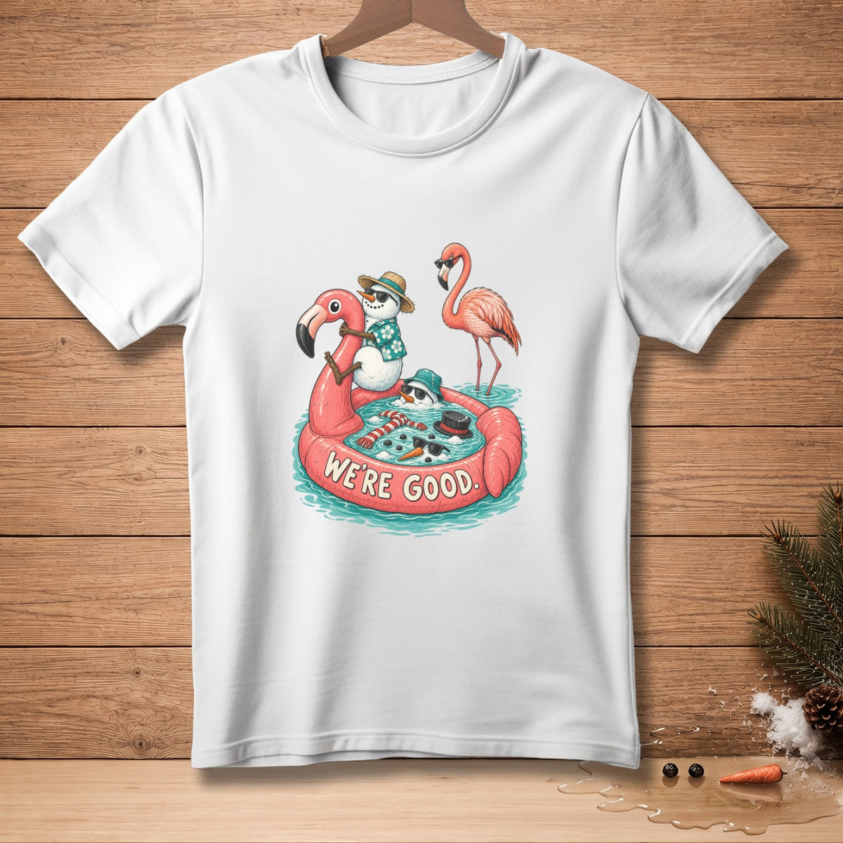 White t-shirt with cartoon snowmen and flamingo on inflatable, text "WE'RE GOOD".