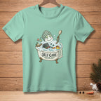 Snowman in bathtub with cucumber slices, towel, and "Self Care" text.