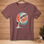 T-shirt with melting snowman pushing a large ball that says "ALMOST THERE".