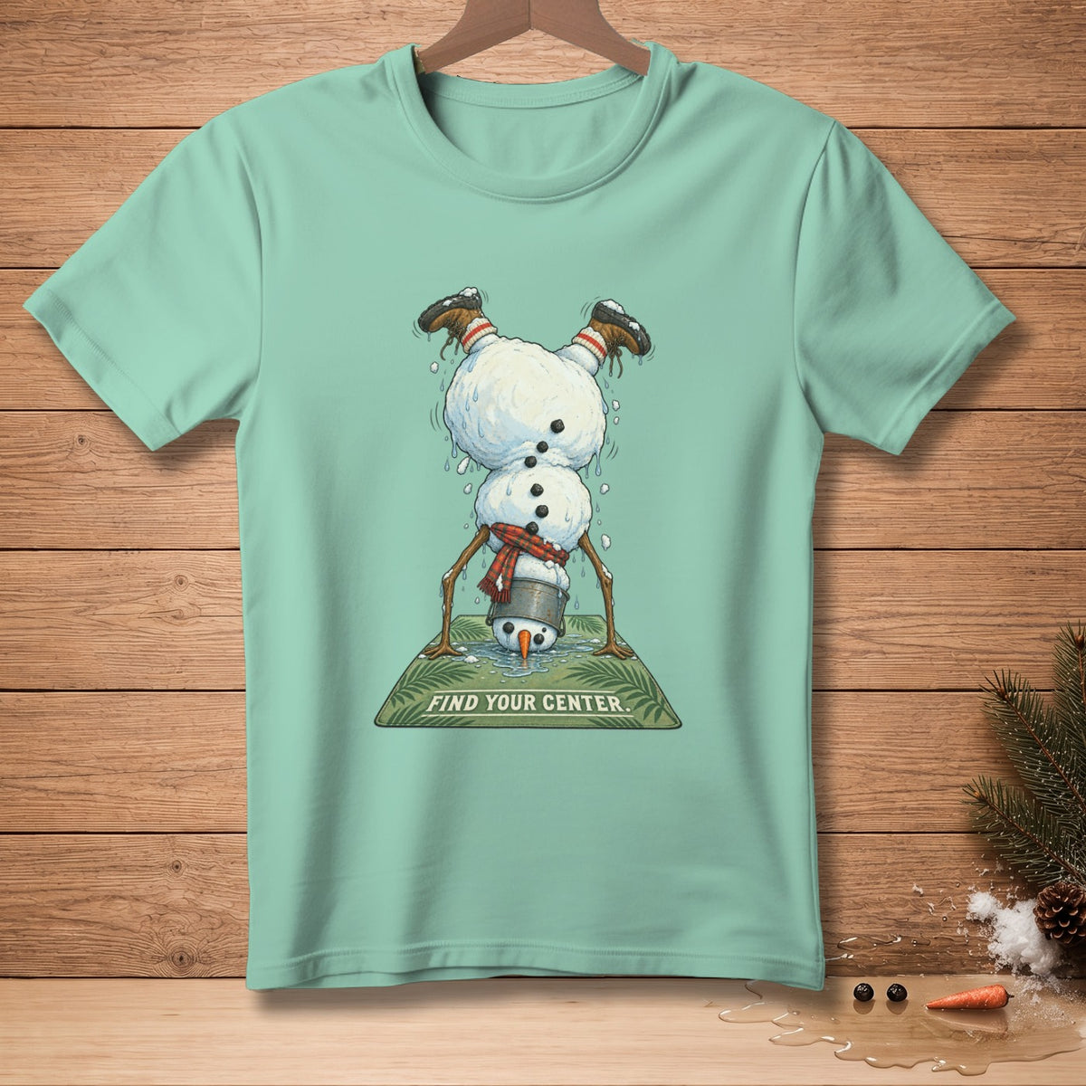 Mint t-shirt with a melting snowman doing a handstand and text "FIND YOUR CENTER."