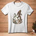 Bigfoot walking past a fallen snowman with a sign reading "Nailed The Walk."