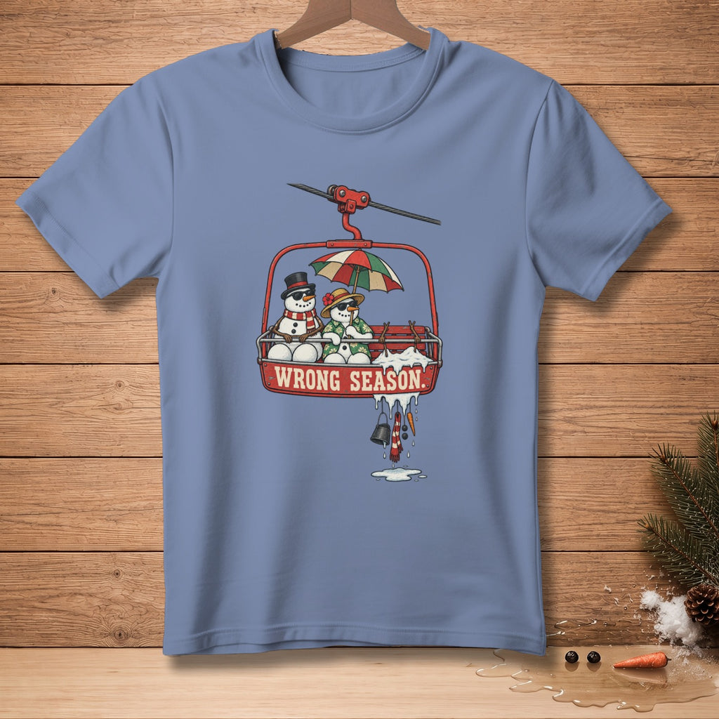 T-shirt with snowmen in a ski lift gondola, umbrella, and "WRONG SEASON" text.