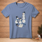 Three snowmen, one large and two smaller, stand near a snowman drawing and scattered accessories.