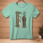 Snowman and Bigfoot hiding behind trees with "Nailed It" sign on shirt.