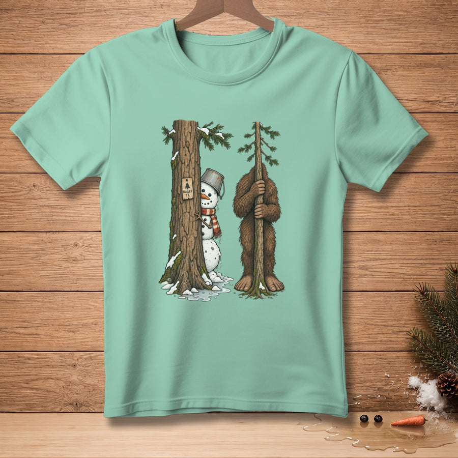 Snowman and Bigfoot hiding behind trees with "Nailed It" sign on shirt.