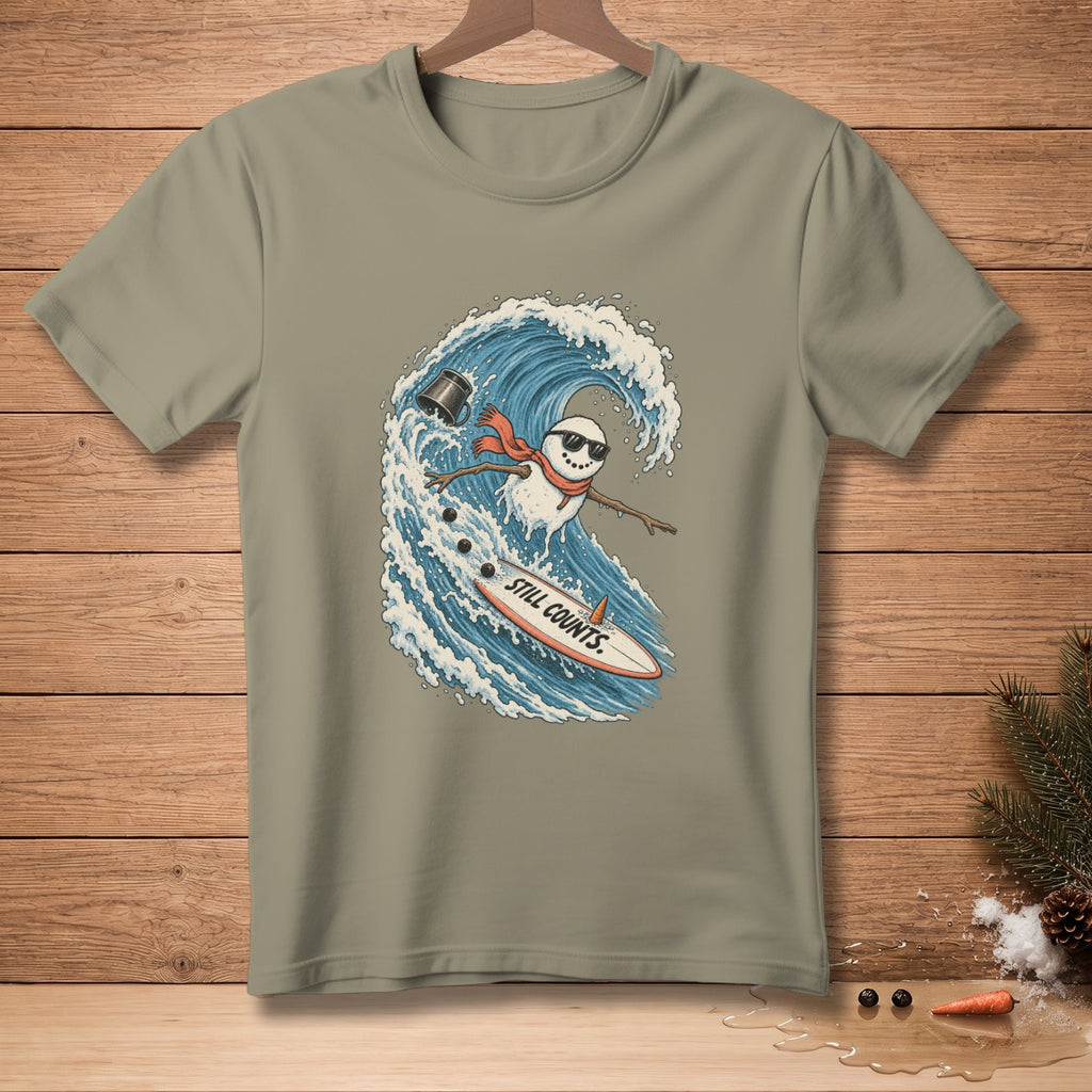 Snowman surfing on a wave with text "STILL COUNTS." on surfboard.