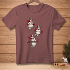Three snowmen wearing scarves and hats jump rope on a mauve t-shirt.