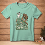 Bigfoot and snowman play shuffleboard on t-shirt graphic with "COUNTS" text.