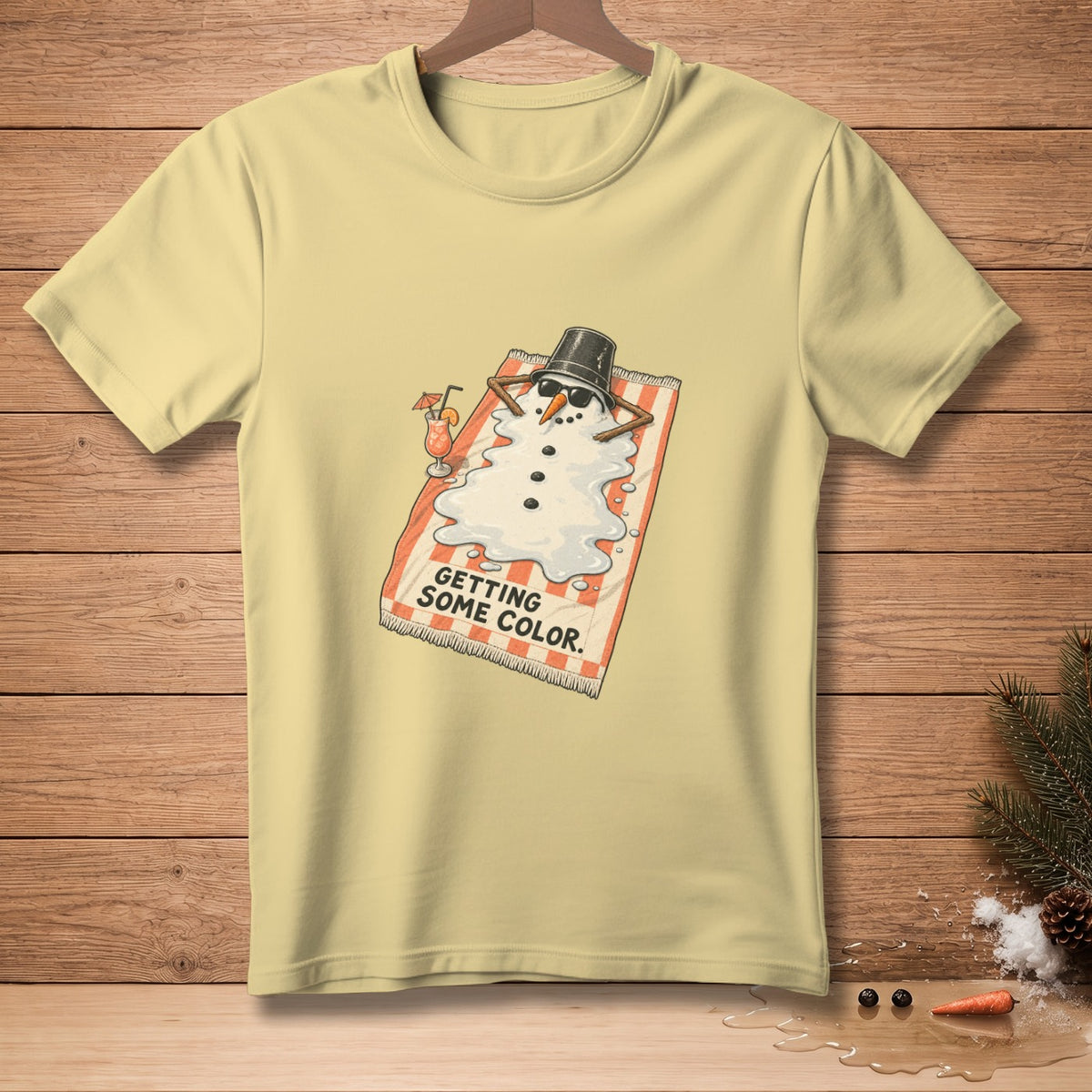 T-shirt graphic: Melting snowman wearing sunglasses, lying on a beach towel, with text "GETTING SOME COLOR."