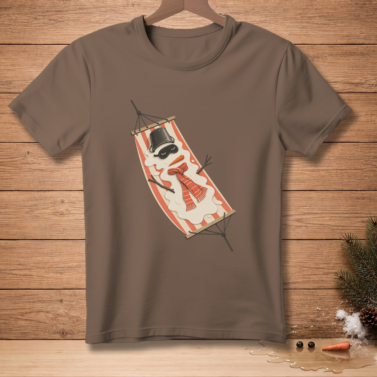 Brown t-shirt with a melting snowman wearing a hat, sunglasses, and scarf in a hammock.