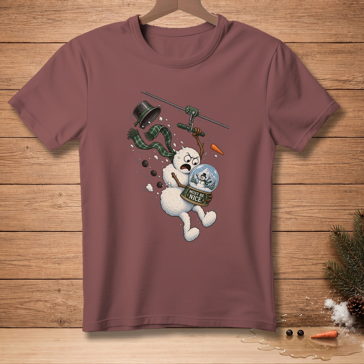 Maroon t-shirt with a cartoon snowman ziplining with a snow globe.
