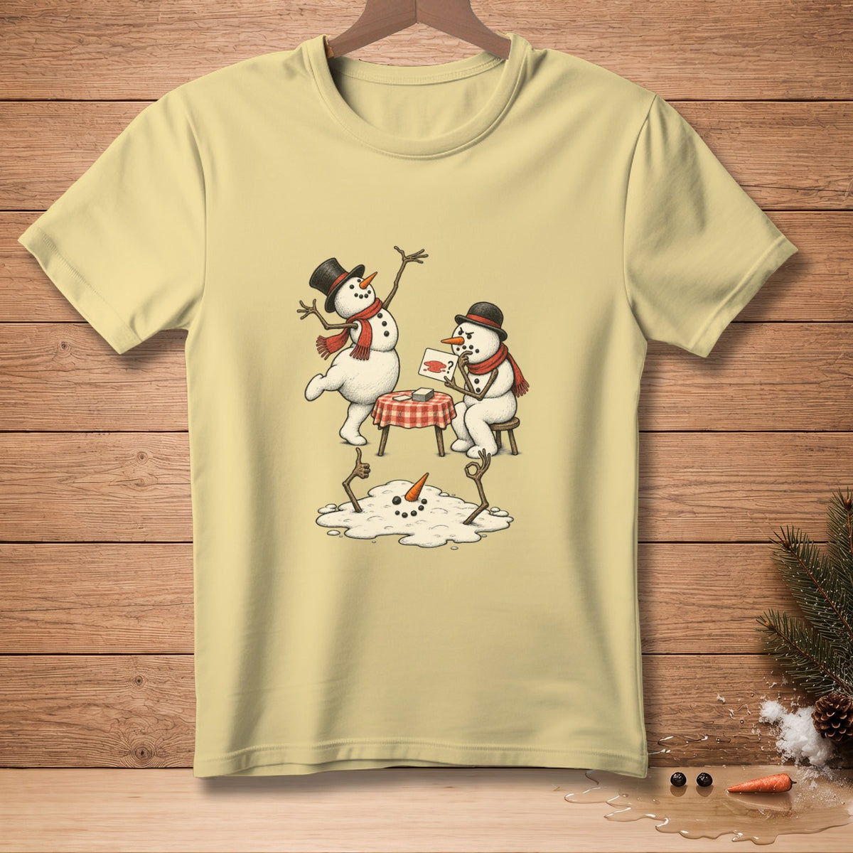 Yellow t-shirt with a drawing of two snowmen and a melting snowman on a table.