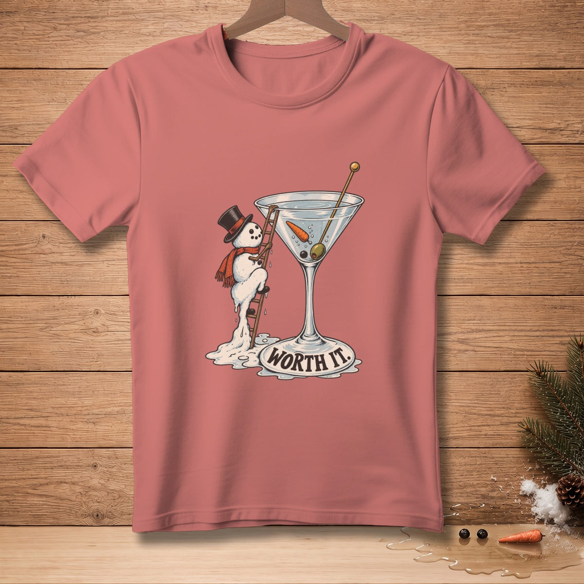 Pink t-shirt with a melting snowman climbing into a martini glass, text reads "WORTH IT."
