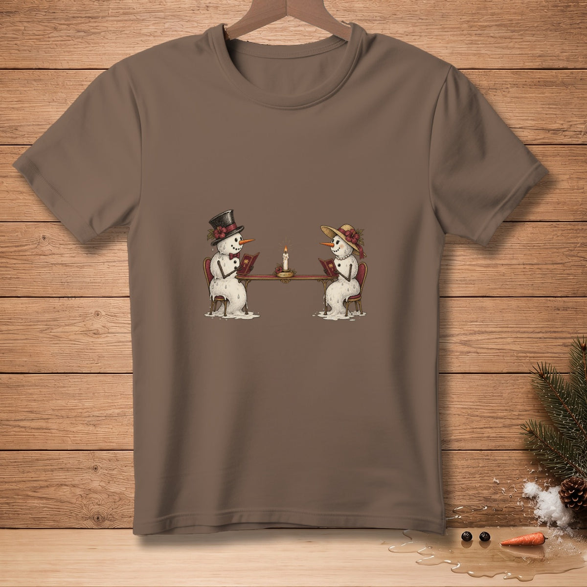 Brown t-shirt with illustration of two snowmen reading at a table by candlelight.