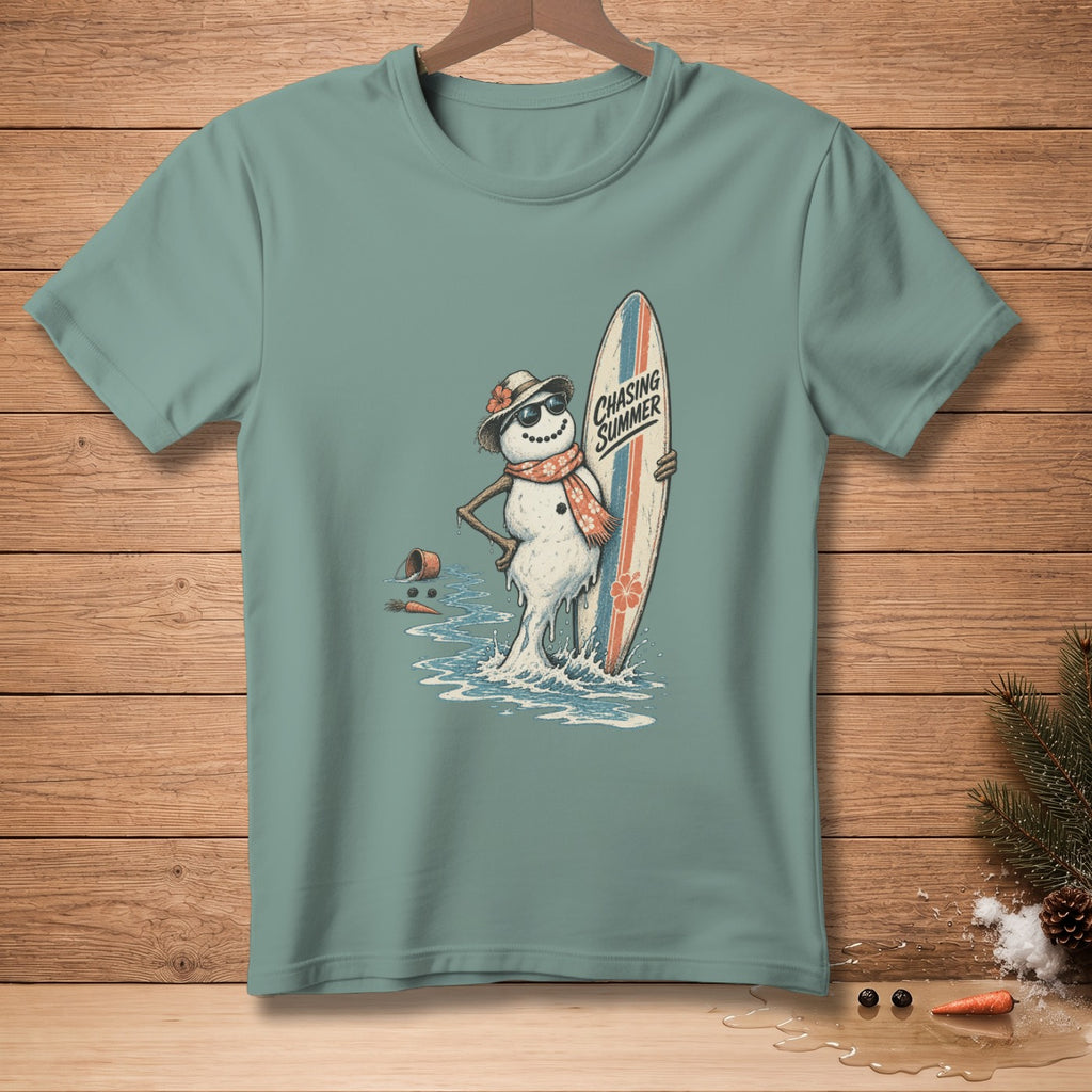 Snowman with sunglasses and surfboard on a teal t-shirt, text reads "Chasing Summer".