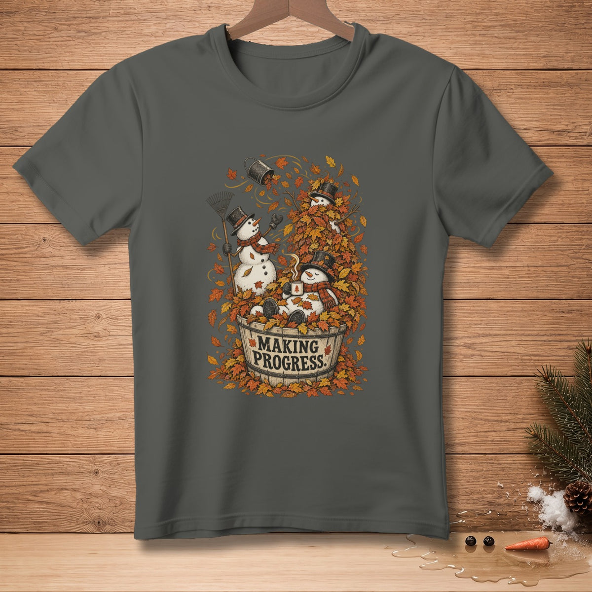 Snowmen playing in fall leaves with text "MAKING PROGRESS" on a gray t-shirt.