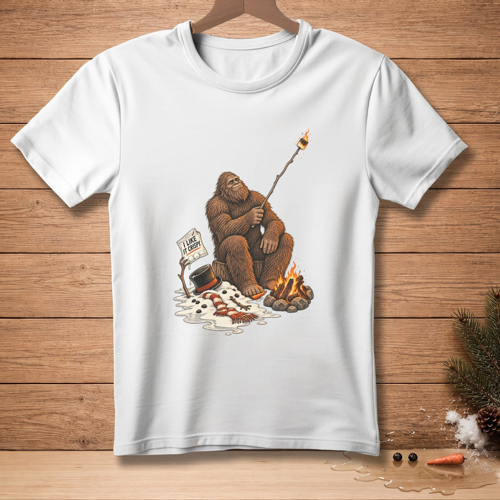 Bigfoot roasting marshmallow over campfire with sign saying "I like it crispy".