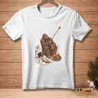 Bigfoot roasting marshmallow over campfire with sign saying "I like it crispy".
