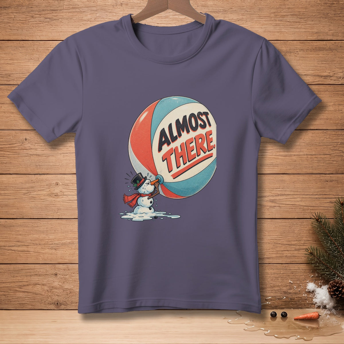 T-shirt graphic of melting snowman holding sphere with text "ALMOST THERE".