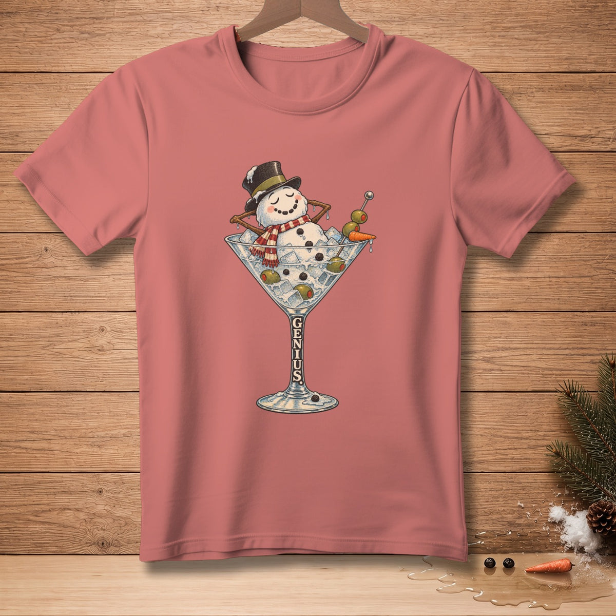 Snowman in martini glass with olives, carrot, and "GENIUS" text on pink t-shirt.