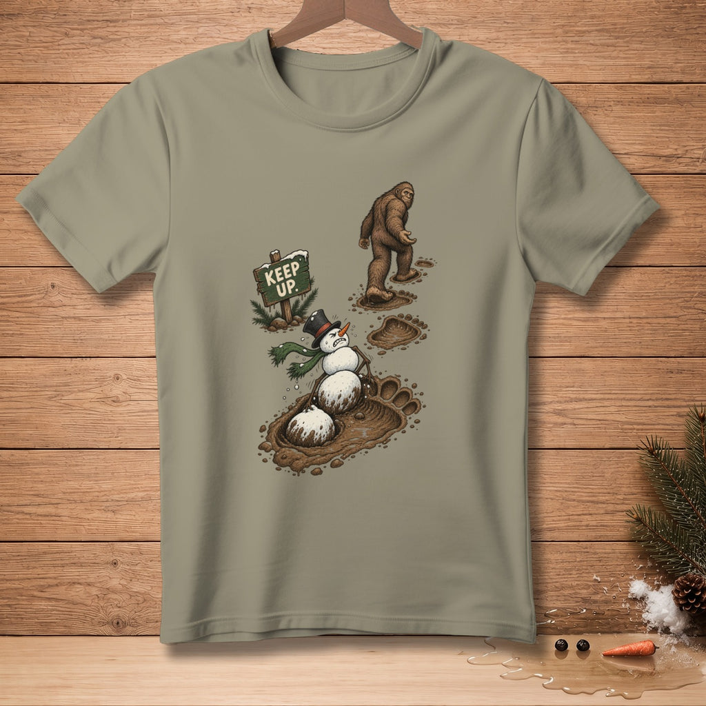 Bigfoot walks past a snowman stuck in mud and a sign saying "Keep Up."