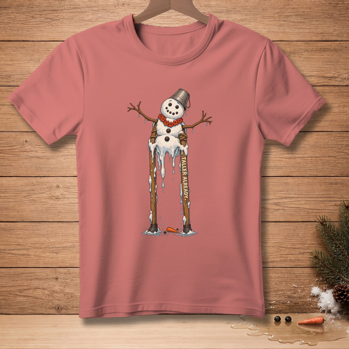 Melting snowman graphic with text "TALLER ALREADY" on a pink t-shirt.
