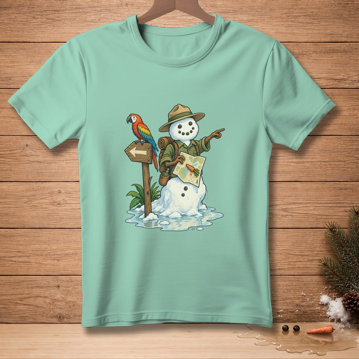 Snowman adventurer with parrot and map points direction on teal t-shirt.