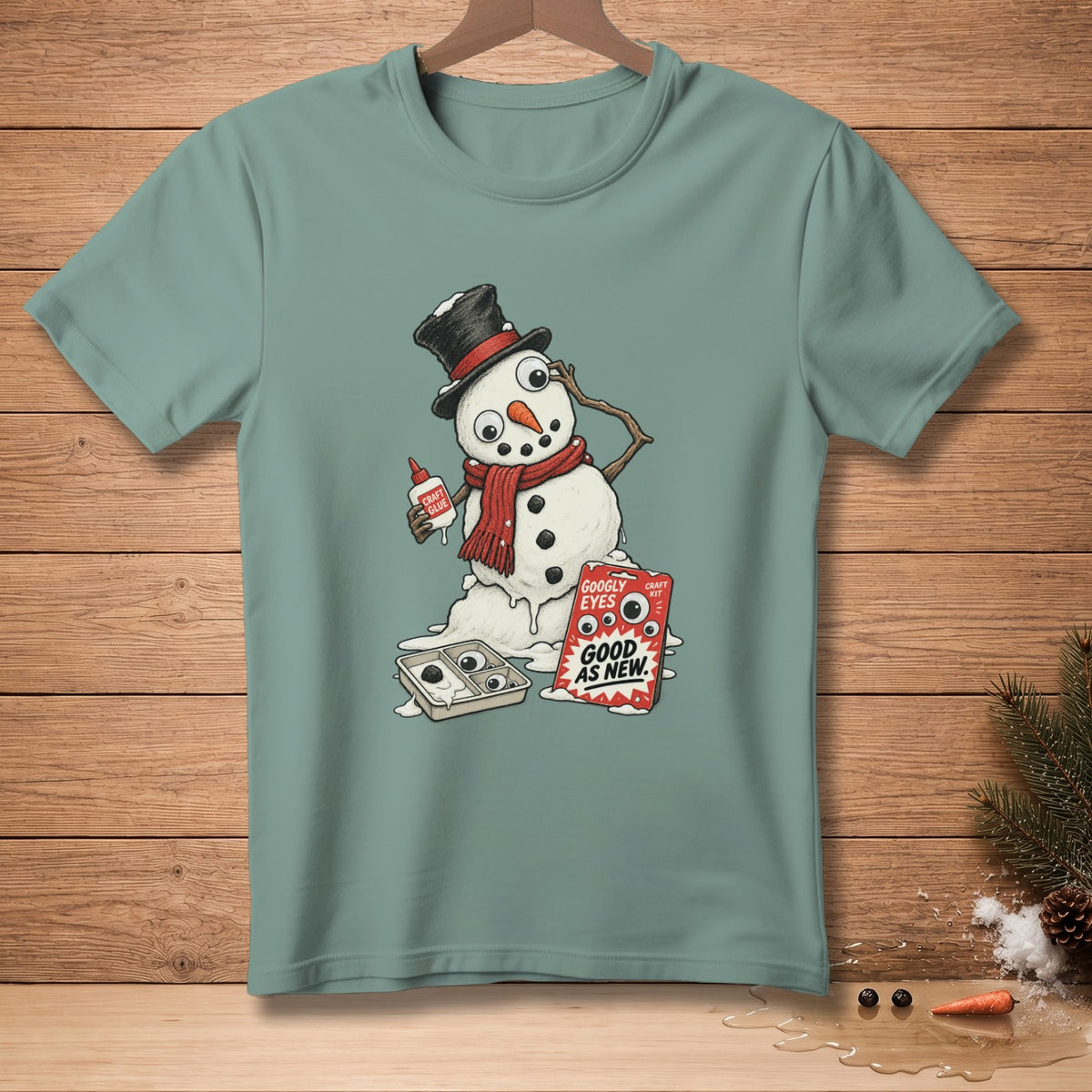 Snowman melting, fixing with craft glue and googly eyes, on a teal t-shirt.