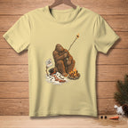Bigfoot roasts a marshmallow over a campfire, with a melting snowman and "I like it crispy" sign.