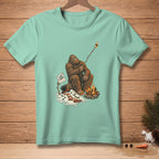 Bigfoot roasts a marshmallow over a campfire next to a melting snowman, text reads "I like it crispy."