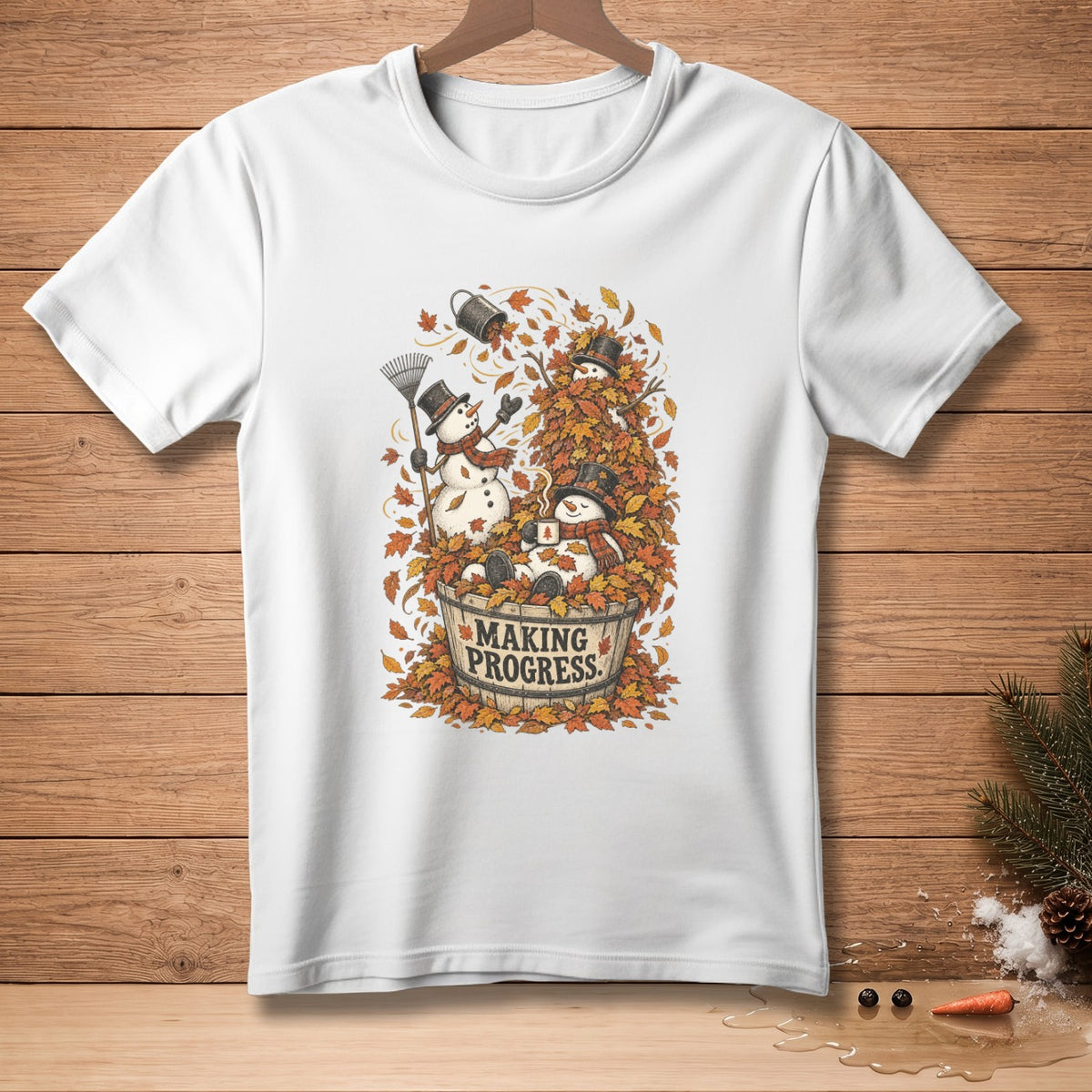 White t-shirt with snowmen in a bucket of leaves, text reads "MAKING PROGRESS."