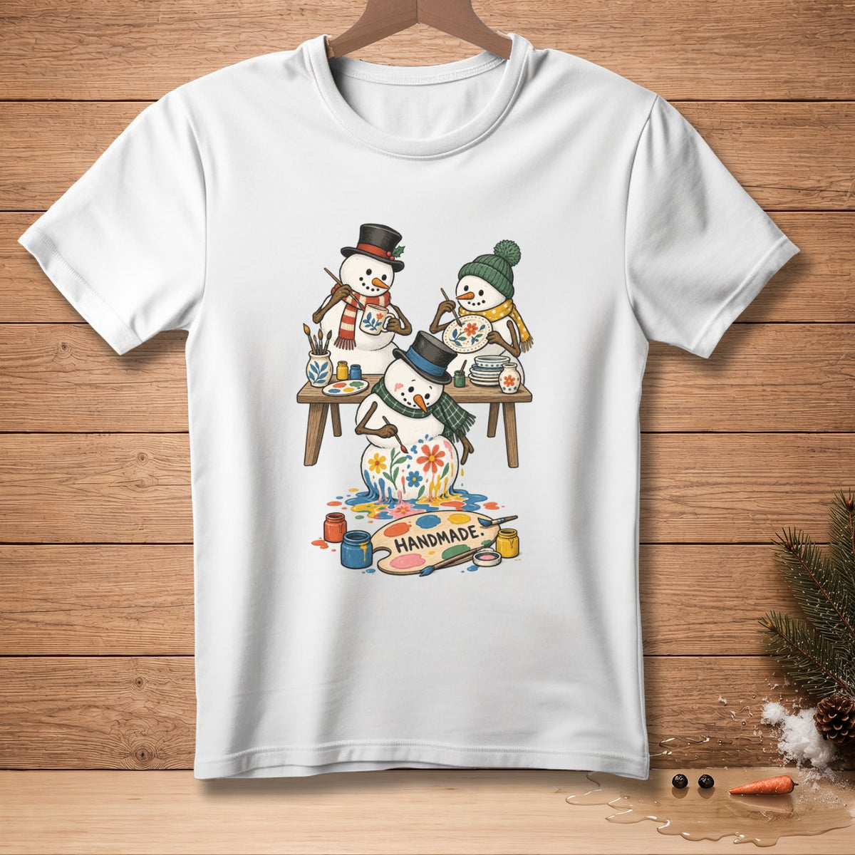 Three snowmen paint a fourth snowman with flowers, text reads "Handmade."