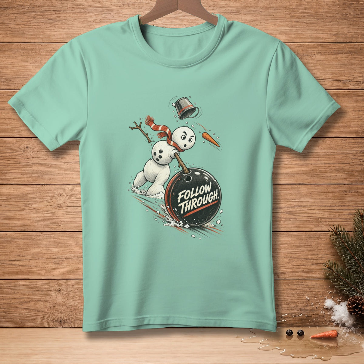 Mint t-shirt with a graphic of a snowman bowling a ball with "FOLLOW THROUGH" text.