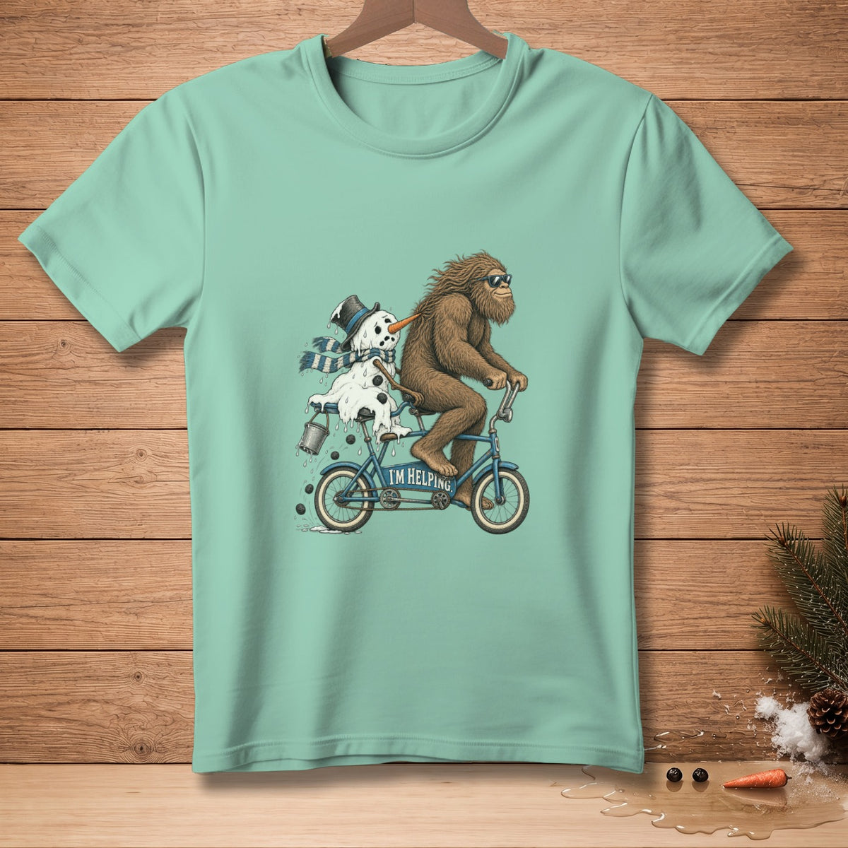 Bigfoot rides a tandem bicycle with a melting snowman that says "I'M HELPING."