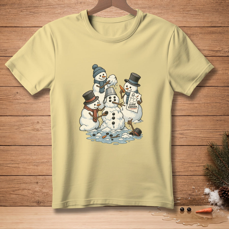 Snowmen assembling a snowman holding a sign that reads "CLOSE ENOUGH."