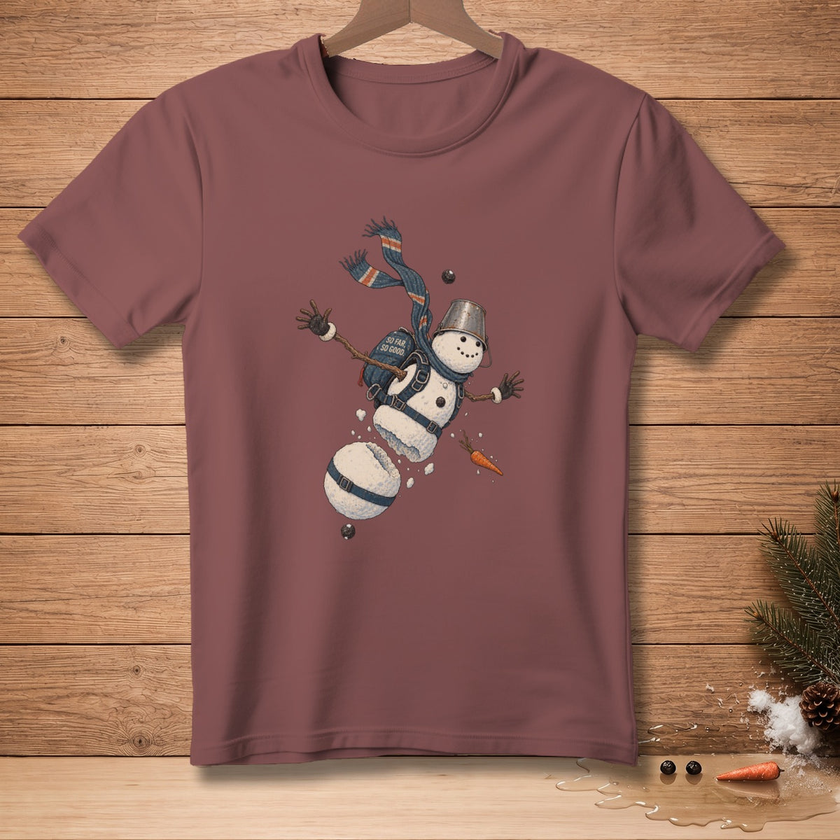 T-shirt with a falling snowman graphic wearing a scarf and bucket hat, reading "So Far So Good".