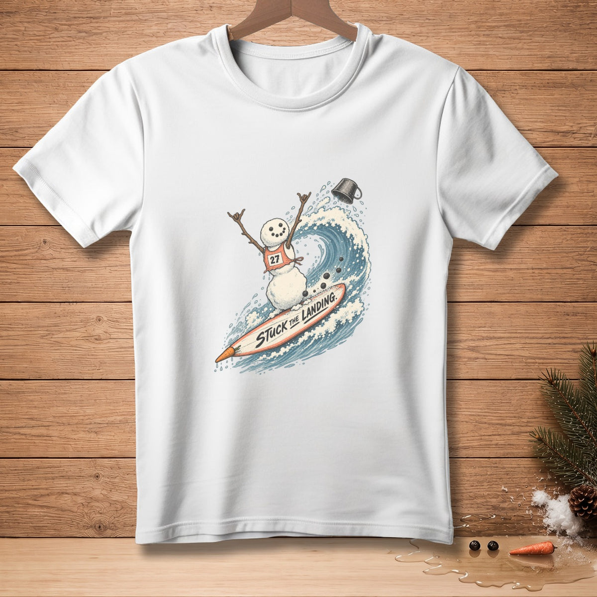 White t-shirt with a snowman surfing a wave on a surfboard with text.