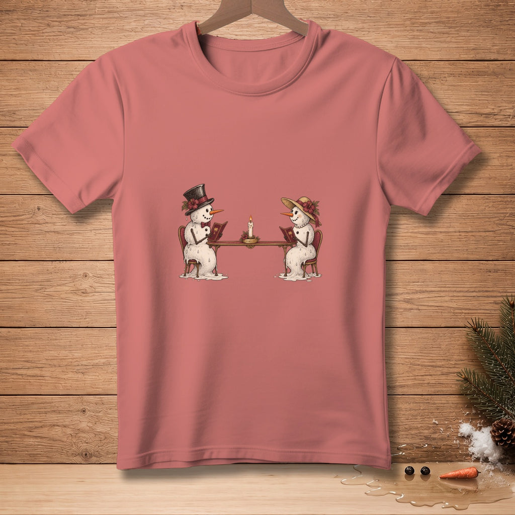 Two snowmen sitting at a table reading books by candlelight on a pink t-shirt.