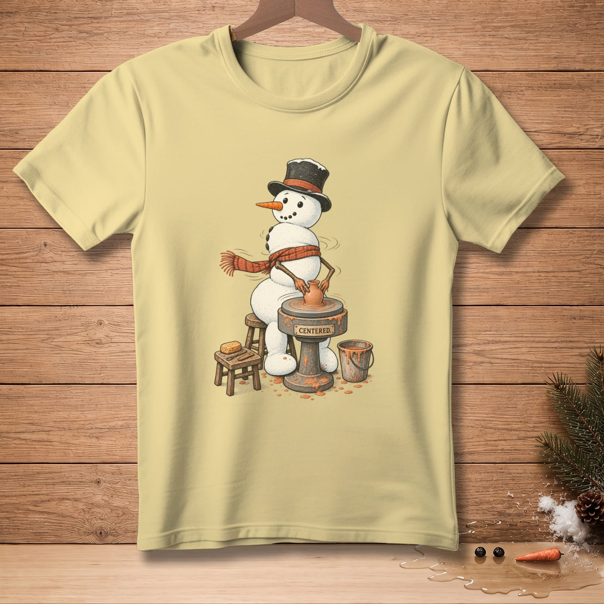 Snowman wearing a top hat and scarf, working on a pottery wheel with the word "CENTERED" on the base.