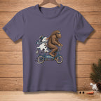 Bigfoot rides a bicycle with a melting snowman, text reads "I'M HELPING".