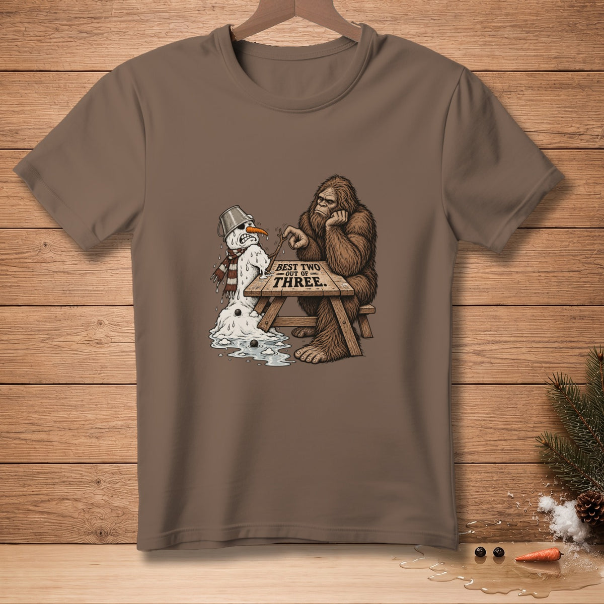 Bigfoot sits with melting snowman, text reads "BEST TWO OUT OF THREE".